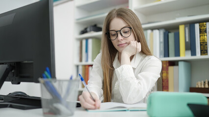 Sticker - Young blonde woman student using computer writing on notebook at university classroom