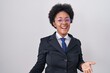© Krakenimages.com - Beautiful african woman with curly hair wearing business jacket and glasses smiling cheerful with open arms as friendly welcome, positive and confident greetings