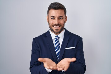 Handsome hispanic man wearing suit and tie smiling with hands palms together receiving or giving gesture. hold and protection