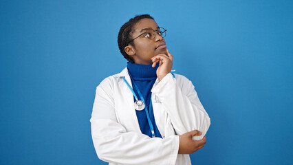 Canvas Print - African american woman doctor standing with doubt expression thinking over isolated blue background