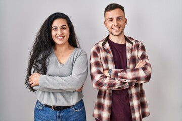 Poster - Young hispanic couple standing over white background happy face smiling with crossed arms looking at the camera. positive person.