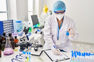 Canvas Print - Middle age woman wearing scientist unifor and medical mask holding vaccine write on clipboard at laboratory