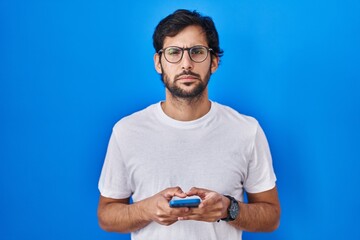 Sticker - Handsome latin man using smartphone typing message skeptic and nervous, frowning upset because of problem. negative person.