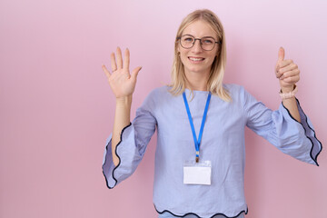 Wall Mural - Young caucasian business woman wearing id card showing and pointing up with fingers number six while smiling confident and happy.