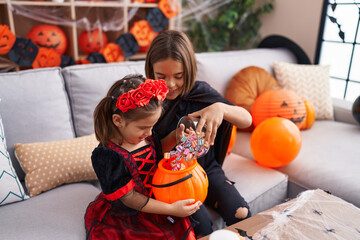 Poster - Adorable boy and girl having halloween party putting candies in pumpkin basket at home