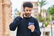 © Krakenimages.com - Young arab man talking on the smartphone and using credit card at street
