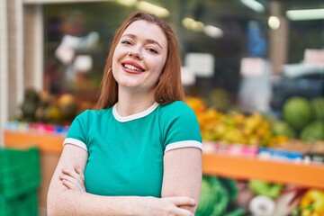 Wall Mural - Young redhead woman standing with arms crossed gesture at street