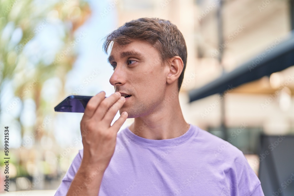 Young caucasian man talking on smartphone with serious expression at street