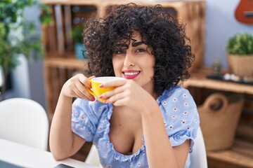 Sticker - Young middle east woman drinking coffee sitting on table at home