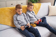 Adorable boys playing video game sitting on sofa at home