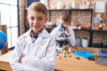 Sticker - Adorable boys students using microscope standing with arms crossed gesture at laboratory classroom