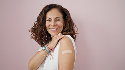 Canvas Print - Middle age hispanic woman smiling confident standing with band aid on arm over isolated pink background