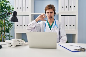 Canvas Print - Young doctor man working on online appointment with angry face, negative sign showing dislike with thumbs down, rejection concept