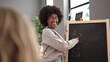 © Krakenimages.com - African american woman teacher smiling confident writing on blackboard at kindergarten