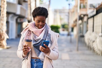 Wall Mural - African american woman using smartphone drinking coffee at street