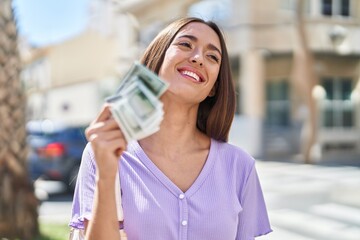  Young beautiful hispanic woman smiling confident holding dollars at street