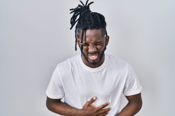 Wall Mural - African man with dreadlocks wearing casual t shirt over white background with hand on stomach because nausea, painful disease feeling unwell. ache concept.