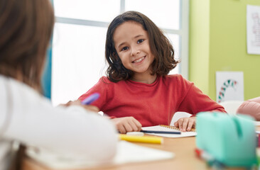 Poster - Adorable hispanic girl student writing on notebook at classroom