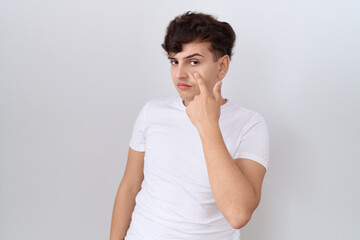 Canvas Print - Young non binary man wearing casual white t shirt pointing to the eye watching you gesture, suspicious expression