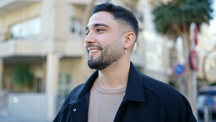 Wall Mural - Young arab man smiling confident looking to the side at street