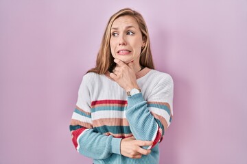 Canvas Print - Young blonde woman standing over pink background thinking worried about a question, concerned and nervous with hand on chin