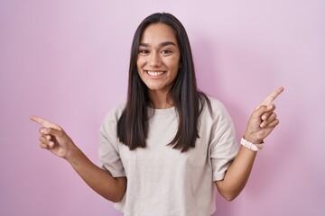 Canvas Print - Young hispanic woman standing over pink background smiling confident pointing with fingers to different directions. copy space for advertisement