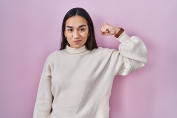 Canvas Print - Young south asian woman standing over pink background strong person showing arm muscle, confident and proud of power