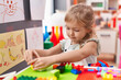© Krakenimages.com - Adorable blonde girl playing with construction blocks sitting on table at kindergarten