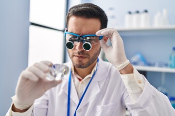 Poster - Young hispanic man scientist looking diamond by magnifying glasses at laboratory