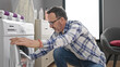 © Krakenimages.com - Middle age man smiling confident washing clothes at laundry room