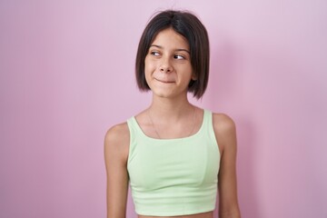 Sticker - Young girl standing over pink background smiling looking to the side and staring away thinking.