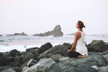 Wall Mural - Woman is practicing yoga, meditating on the beach.