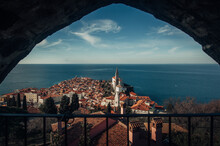 A Panoramic View Of Piran, Slovenia Captured From The Castle Above The Town, Showing The Red-tiled Roofs Of The Buildings, The Harbor, And The Adriatic Sea In The Background.
