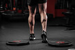 © VlaDee - Trained man's legs with muscular calves in sneakers in fitness training gym