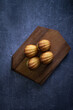 Freshly baked madeleine cakes on a wooden plate and dark table