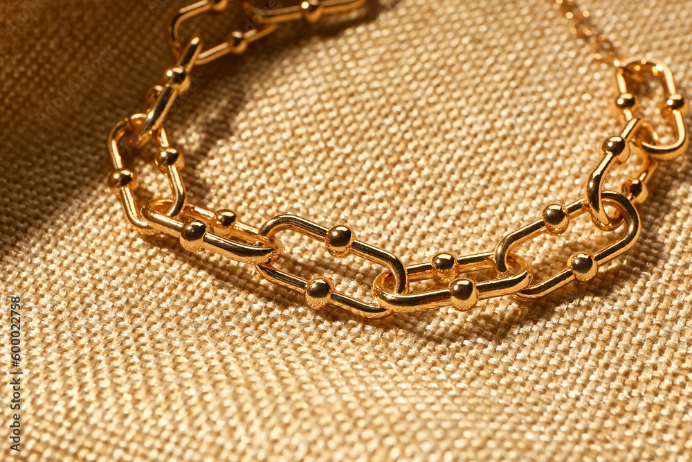 Beautiful chain bracelet on beige fabric background