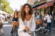 © wetzkaz - young adult attractive smiling woman has fun and joy riding a bicycle on a side street in a small town, fictional location. Generative AI