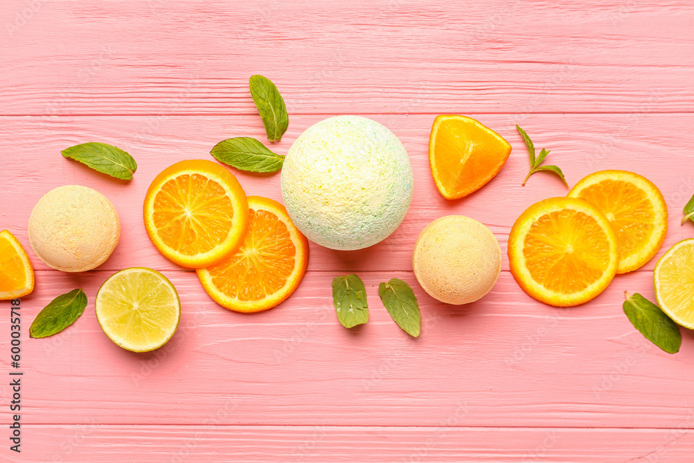 Bath bombs with orange slices and leaves on pink wooden background