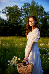 Poster - portrait of a beautiful red-haired girl in a light summer dress in nature with a basket of flowers