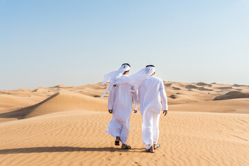 Wall Mural - Two middle-eastern emirati men wearing arab kandura bonding in the desert