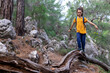 © zhukovvvlad - A boy with a backpack walks along the trunk of a fallen tree, a child walks through the forest, a kid is exploring nature..