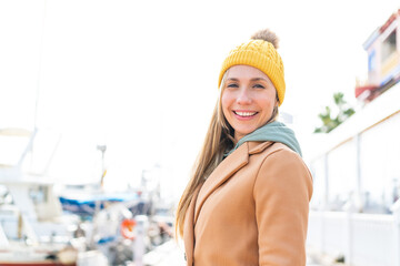 Wall Mural - Young blonde woman wearing winter jacket at outdoors smiling a lot