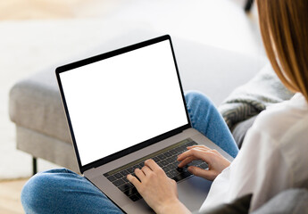 Young woman using laptop with blank screen. Female watching webinar, training or online works. Copy space, mock-up for your design, typing text