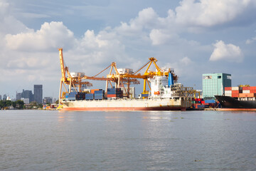 Cargo ship at dock, port or harbor. To loading cargo container, work with crane. Concept of business and industry i.e. shipping, logistics, international trade, freight transport and import export.