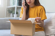 © KMPZZZ - Angry bad, complaint asian young woman opening carton box, received online shopping parcel wrong product order from retail store, using mobile phone talking with support shop want to return package.