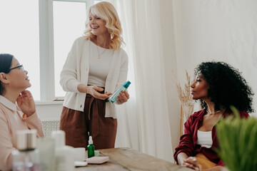 Sticker - Three confident mature women smiling while examining beauty products together