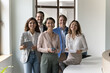 Portrait of modern business startup team members, entrepreneurs, older 55s and younger 35s businesspeople standing in well decorated office environment, smile look at camera. Professional occupation
