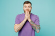 Young shocked surprised amazed fun man he wears purple t-shirt look camera cover mouth with hands isolated on plain pastel light blue cyan background studio portrait. Tattoo translates life is fight.