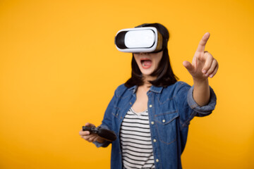 Poster - Young asian woman happy success wearing virtual reality headset game entertainment and holding joystick controller isolated on yellow background. Winner of cyber future video game concept.