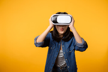 Poster - Young asian woman happy success wearing virtual reality headset game entertainment isolated on yellow background. Winner of cyber future video game concept.
